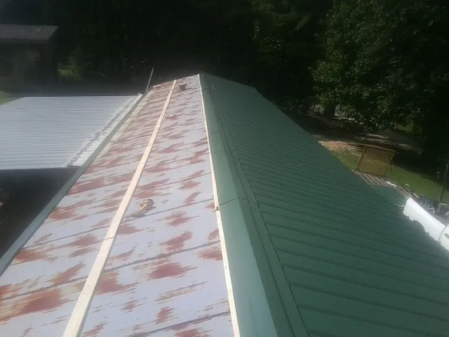 Old rusted panels beside newly installed green metal roofing — Wind Damage Roof Repair by Roofing Brothers in Earth City