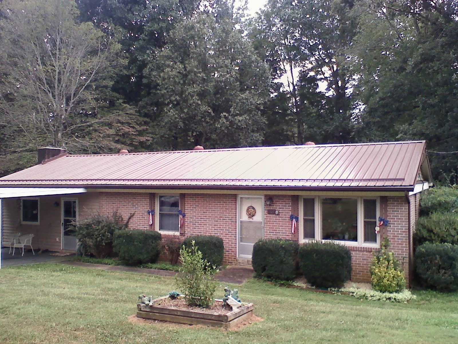 Bronze metal roof on a brick ranch home with a carport in Earth City