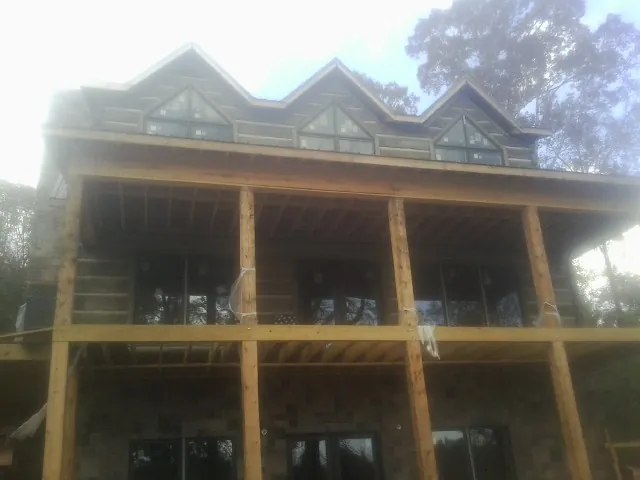 Dormers and porch framing on a large log home under construction — Roof Coating work by our crew in Earth City