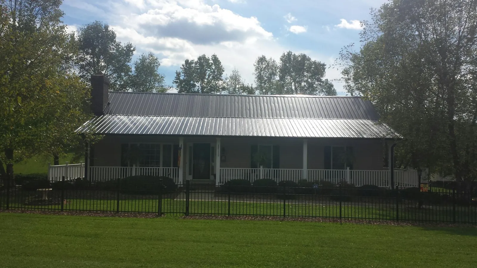 Gray metal roof on a brick ranch with a full width front porch — Gutter Guard Installation work by our crew in Earth City