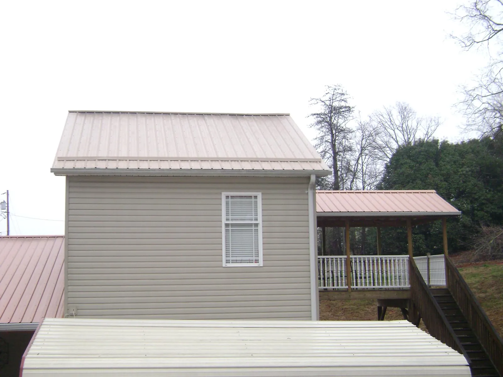 Tan metal roofs on a two story addition and attached porch, from a Roof Replacement job in Earth City