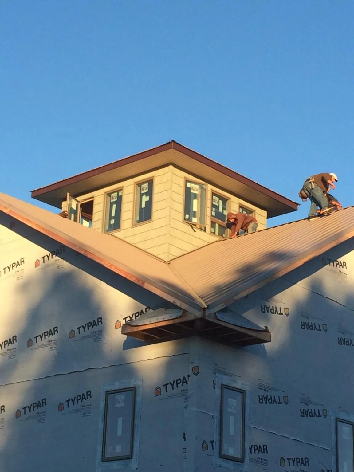 Roofers working around a rooftop cupola on a new metal roof at sunset — Roof Waterproofing in Earth City by Roofing Brothers